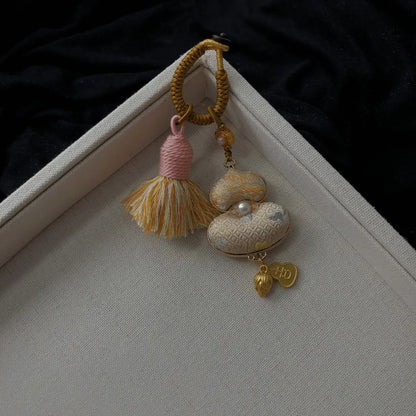 Ivory textile gourd bag charm with floral detail and tassel