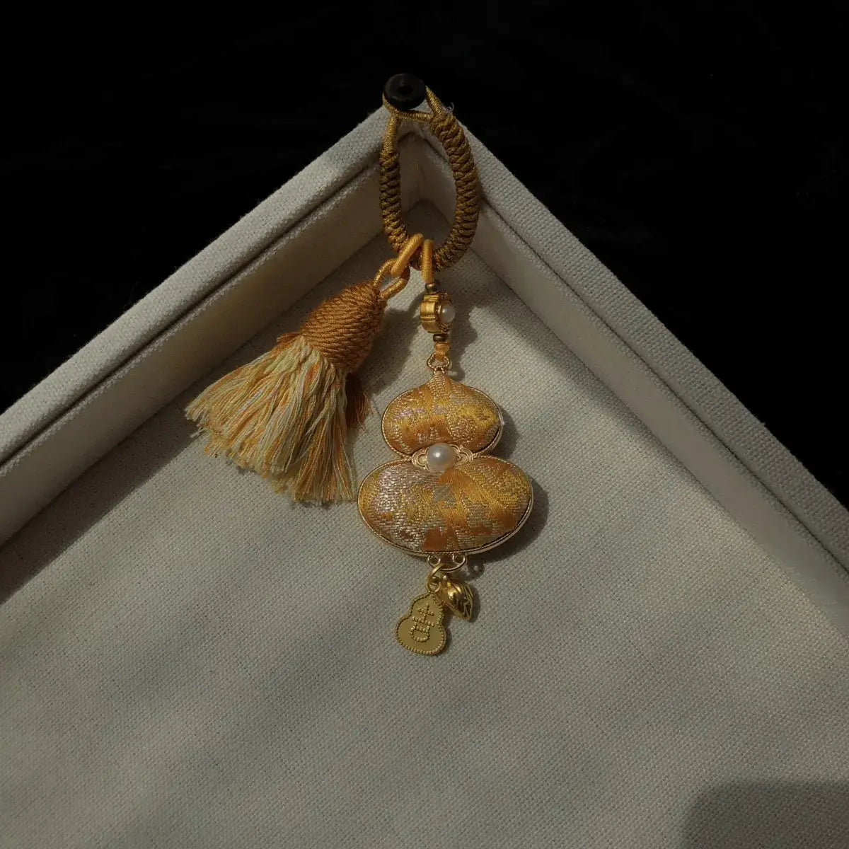 Yellow textile gourd bag charm with floral detail and tassel