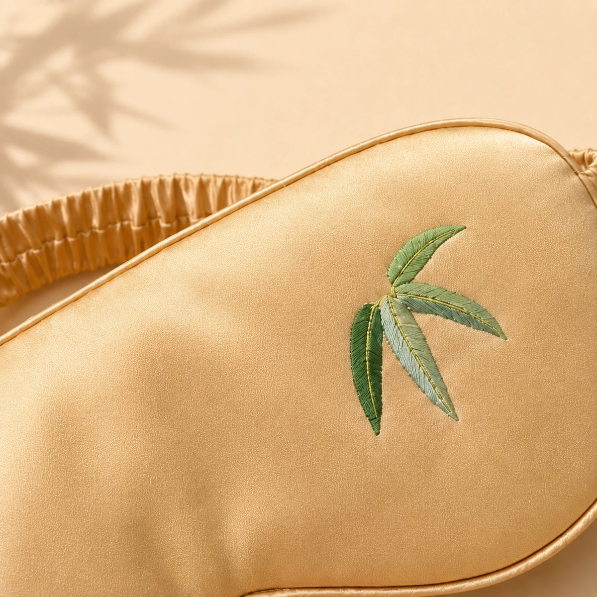 Close-up of bamboo-leaf embroidery on a Champagne mulberry silk sleep mask