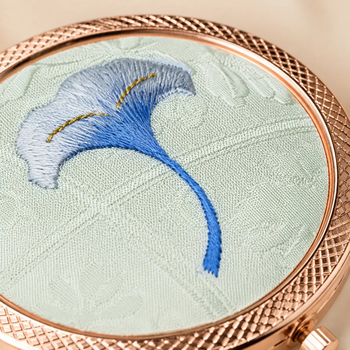 Close-up of blue ginkgo embroidery on the silk compact mirror