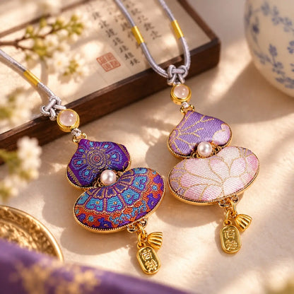 Purple and pink embroidered gourd pendants resting on elegant silk fabric.