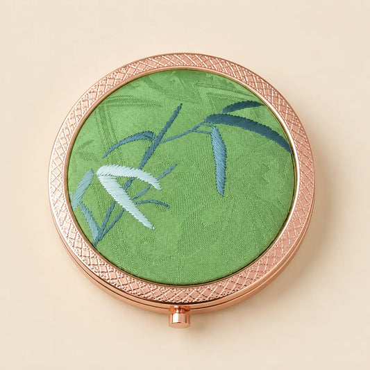 Green Bamboo hand-embroidered silk compact mirror held in the hand