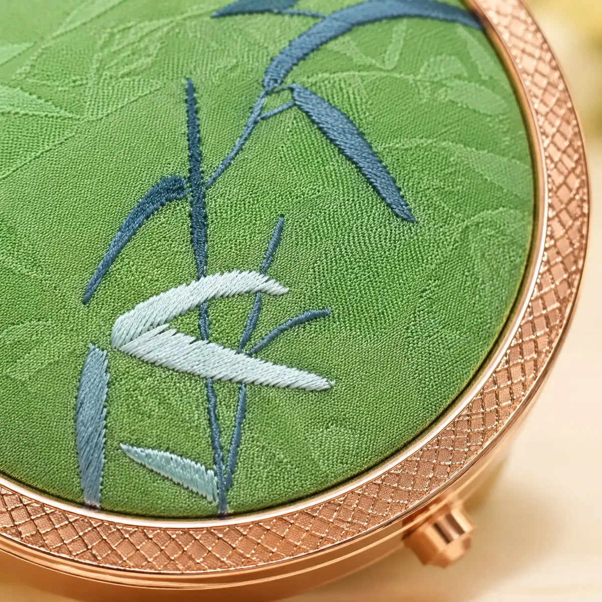 Close-up of blue ginkgo embroidery on the silk compact mirror