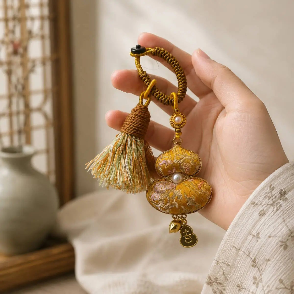Hand holding a yellow handcrafted textile gourd bag charm